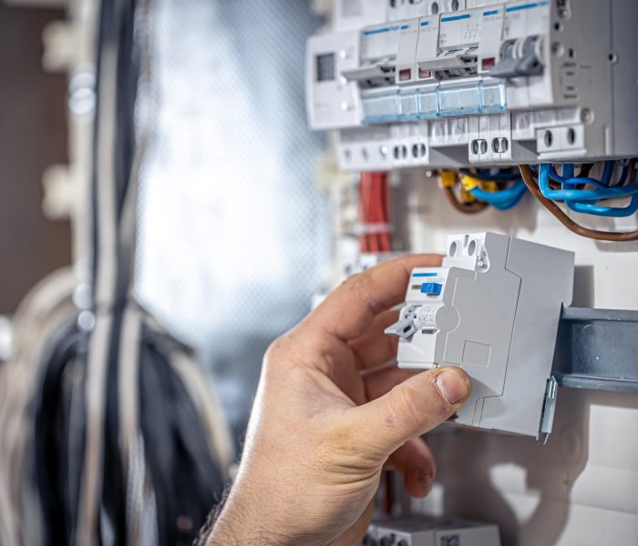 Male electrician at the checkout counter on a blurred background of a switchboard.